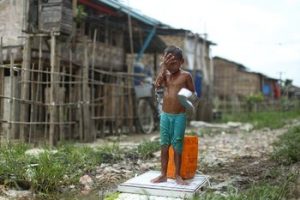 A young boy washes his face in a squatter settlement in Hlaing Tharyar Township in Rangoon which sees regular flooding during monsoon. (Photo: Hkun Lat/ Myanmar Now.)