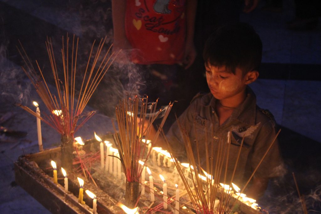 A young boy lights a candle. (Photo: Libby Hogan / DVB)