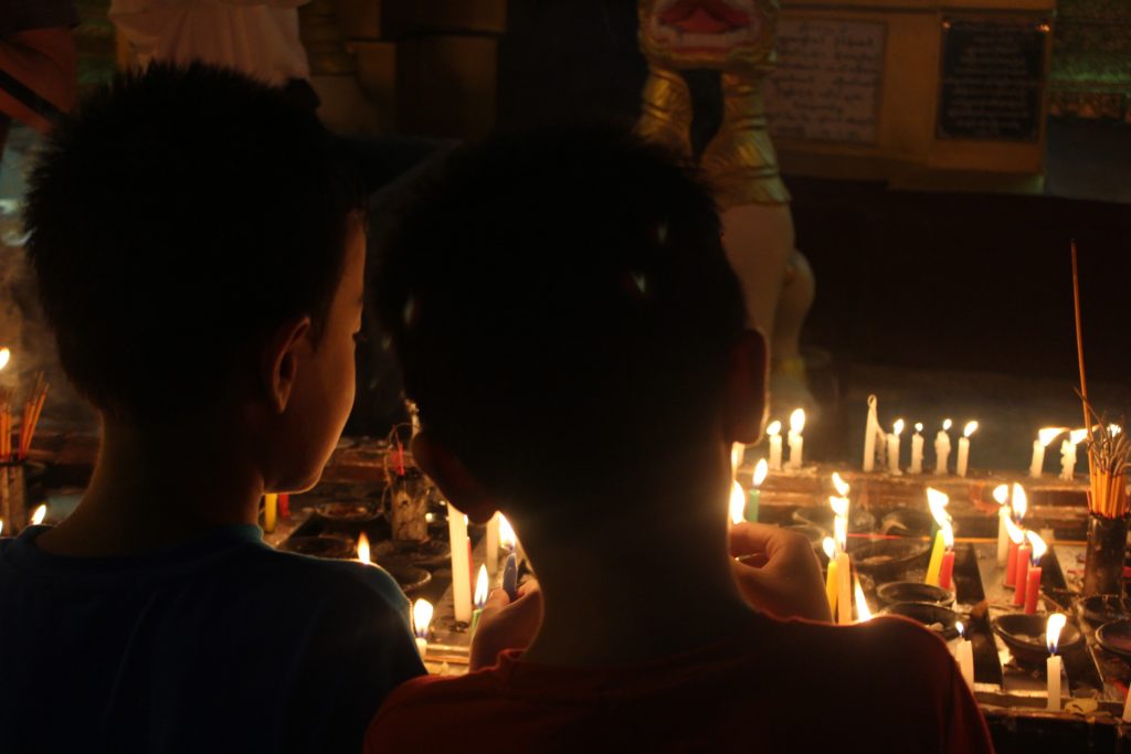 Two children gather in front of the candle display inside Shwedagon Pagoda. (Photo: Libby Hogan / DVB) 