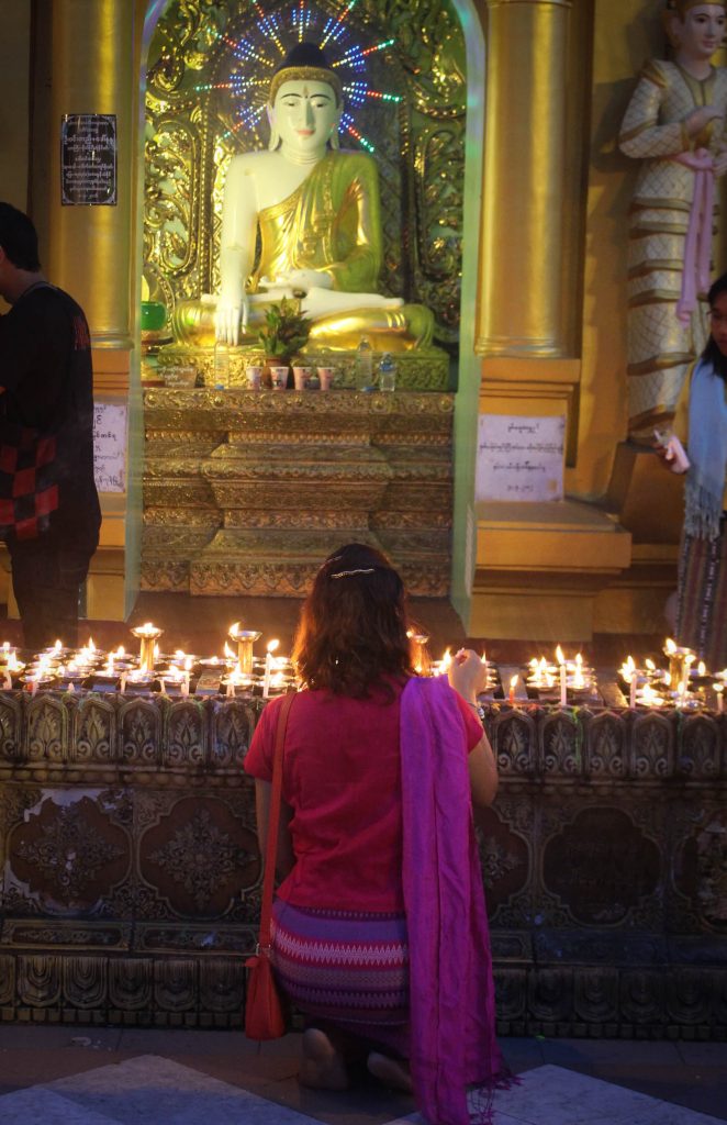 A lady kneels infront of a Buddha statue. (Photo: Libby Hogan / DVB)