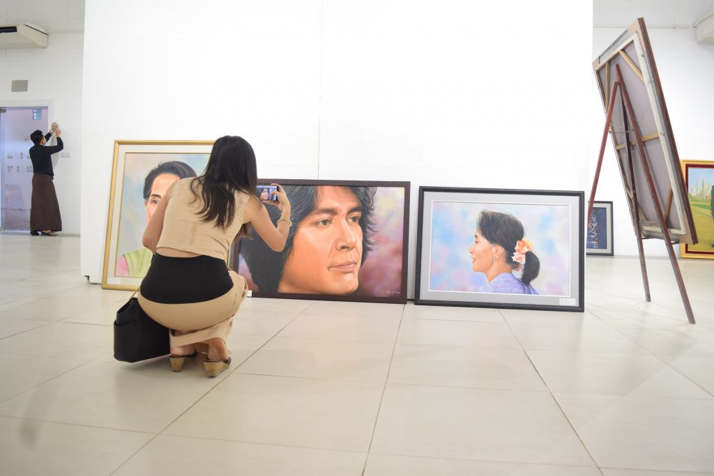 A young woman photographs some of the works at The Yangon Gallery. (PHOTO: Kimberley Phillips / DVB)
