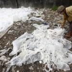 A woman spreads out used plastic bags to dry near a railway line in Yangon