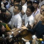Aung San Suu Kyi is surrounded by reporters as she holds her first news conference at the headquarters of her NLD party in Yangon