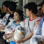 Migrant workers from Myanmar who were trapped in floods and have been out of work for weeks, hold food rations in Thailand’s Ayutthaya province