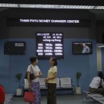 Women chat in front of an exchange rate board at a money changer in Rangoon (Reuters)