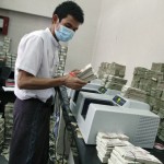 An employee counts Myanmar kyat banknotes in a bank in Yangon