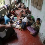 People eat food distributed at a Buddhist monastery used as a collective shelter for those displaced by recent violence in Sittwe