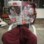 A man reads the newspaper outside his home near the ballot station during the by-elections in Yangon