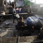 Muslim boys cook on a boat at a beach near a refugee camp outside of Sittwe