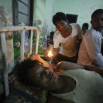 A man looks at the wound of an injured person at a hospital in Kyuktaw township