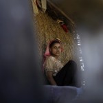 A Muslim woman is reflected in mirror inside her house in Paik Thay village