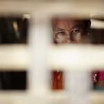 A woman looks out from a shack in a slum in the industrial suburbs of Yangon