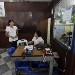 Workers chat as they sit in a public call office phone shop at the Post and Telecommunications division head office in Yangon