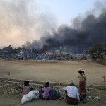 Smoke rises as people look on in Meikhtila