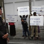 A policeman stands guard near a group of Rohingya people living in Thailand holding signs as they protest in front of Myanmar’s embassy in Bangkok,