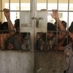 Police officer stands guard near illegal migrants from Myanmar at an immigration detention centre in Medan in Indonesia’s North Sumatra province