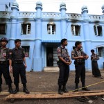 Police stand in front of a mosque and school dormitory that were damaged in a fire in Yangon