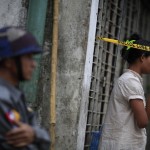 A woman stands behind a police line near a mosque and school dormitory that were damaged by a fire in Yangon