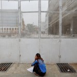 A woman speaks on the phone while reading newspapers outside a construction site in Yangon