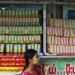 A woman sells lottery tickets beside a street in Yangon
