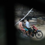 People ride on a motorcycle as they are pictured from the cracked glass of a window at Htan Kone village, in Myanmar’s northern Sagaing region