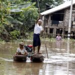 Residents ride a boat on a flooded area as they transport aid for their village at Kawlin township, Sagaing division, Myanmar
