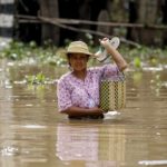 A woman wades through a flooded road in a village at Kawlin township, Sagaing division, Myanmar