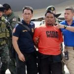 Members of the Philippine National Police intelligence escort Mohammad Ali Tambako, founder and leader of the Justice Islamic Movement, upon arrival at Villamor Air Base in Manila