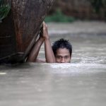 A boy moves his boat in a flooded village outside Zalun Township, Irrawaddy Delta