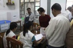 Suu Kyi presents her ID to election officers as she is checked off the voter registrar. (PHOTO: DVB)