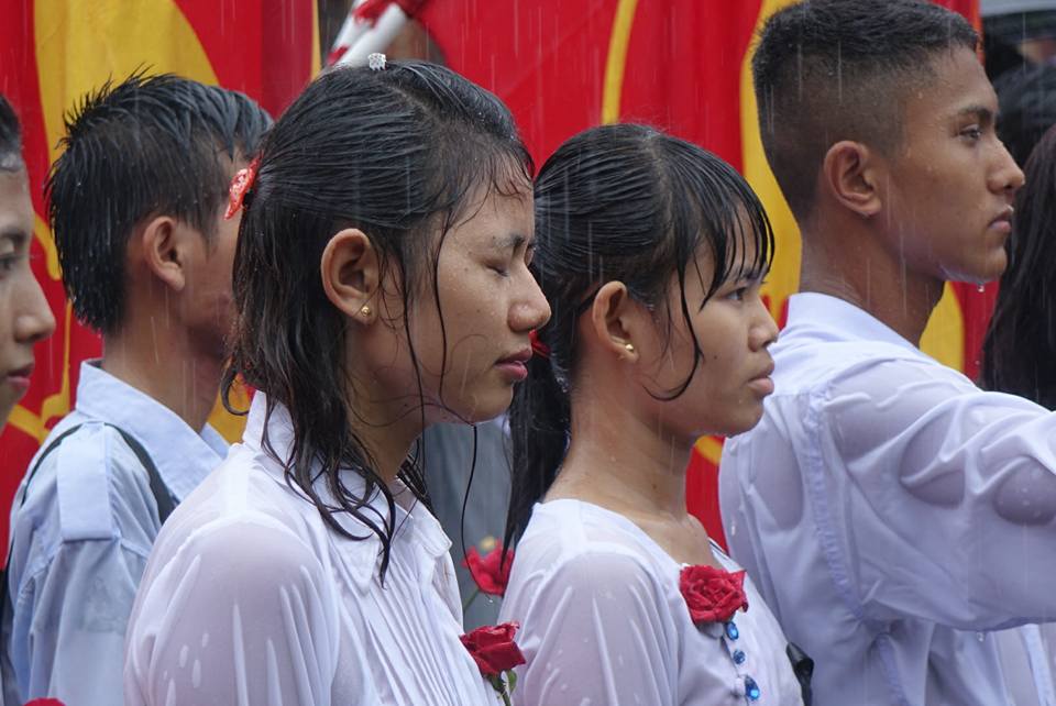 Students stand in the rain in Rangoon at an event to mark Martyrs' Day on 19 June 2016.