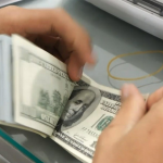 A Kanbawza (KBZ) Bank clerk counts out $100 USD bills (Credit- DVB)