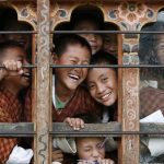 School children react to the camera through the window of their classroom in a school in Thimphu